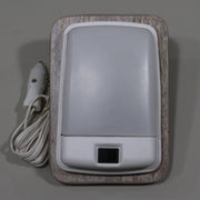 A 12 volt reading light with a cigar plug, light brown base and trim, connected to a white power cord.