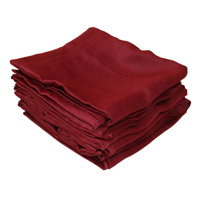 A stack of folded  burgundy fabric curtains on a plain white background.