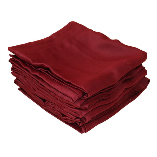 A stack of folded  burgundy fabric curtains on a plain white background.