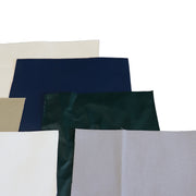 A stack of patch swatches in various colors, including cream, navy blue, dark green, beige, white, and light gray, arranged on a plain white background.