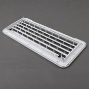 A white rectangular plastic vent cover or grille insert with a slotted grid design, photographed on a dark gray surface.
