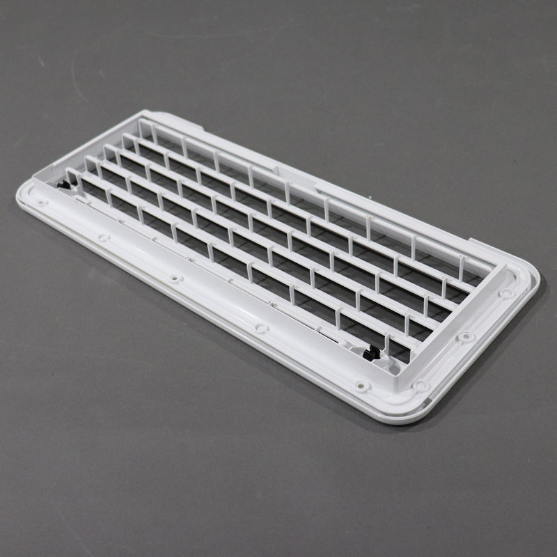 A white rectangular plastic vent cover or grille insert with a slotted grid design, photographed on a dark gray surface.