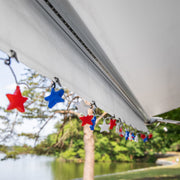 Decorative string with red, white, and blue stars hanging from a awning over a natural landscape.