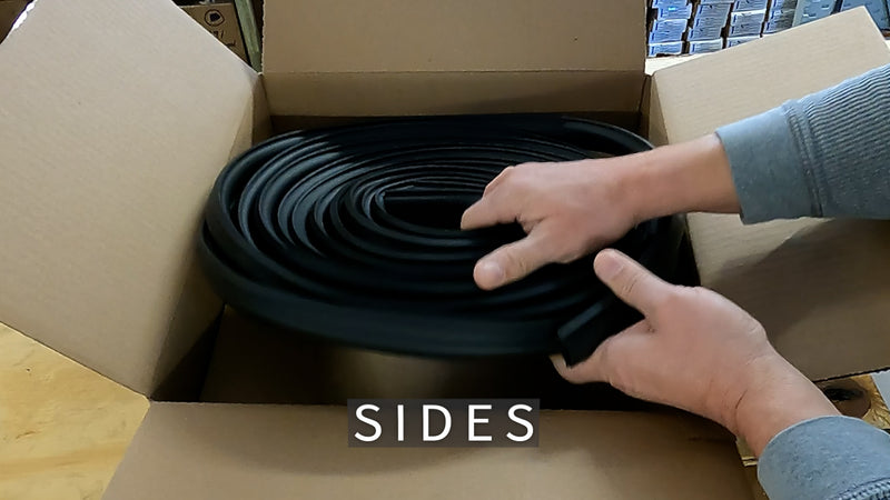 Person handling a roll of black material labeled 'SIDES' inside an open cardboard box.