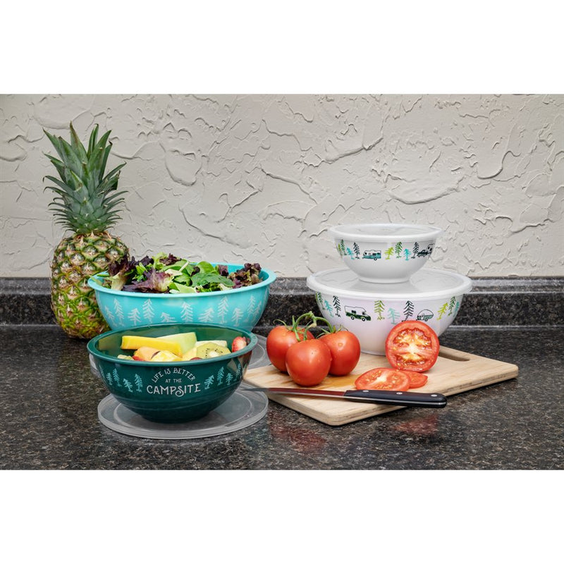 A set of four multicolored nesting bowls with a camping design, displayed with a small bowl on top, followed by a medium, large, and x-large bowl nested within each other. The bowls are on a kitchen counter with a pineapple and some sliced tomatoes in the background.
