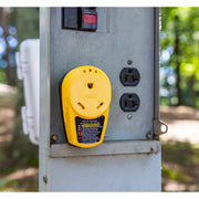 A yellow Power Grip RV 30-Amp Circuit Analyzer Adapter with Integrated Surge Protection plugged into a power outlet outdoors.