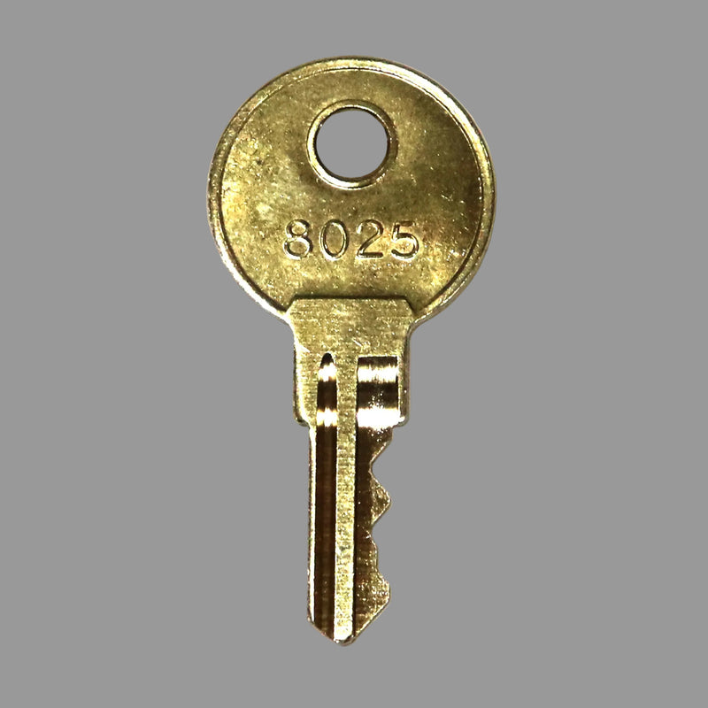 A gold-colored metal key with the number 8025 engraved on the top.