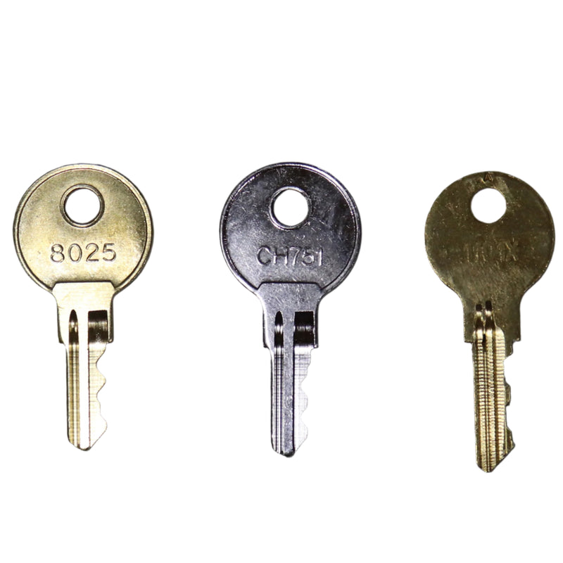 Three metal keys with different numbers engraved on them, placed side by side on a grey surface.