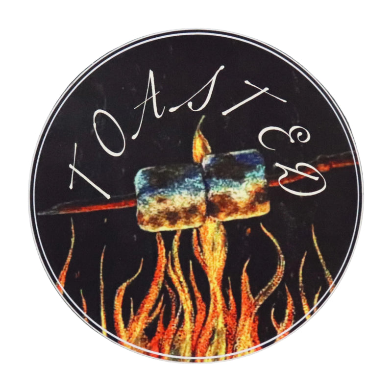 A round sticker with artwork depicting marshmallows being toasted over a campfire, with the word 'TOASTED' written above.