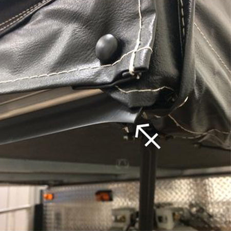Close-up of a black bed seal installed on the corner of a recreational vehicle's bed, showing the seal's bead fitting into the bed track.
