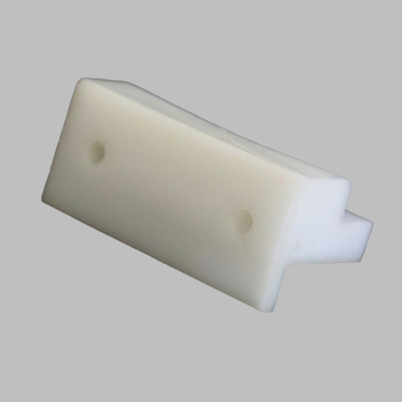 A white plastic bed slide stop bracket on a dark background.