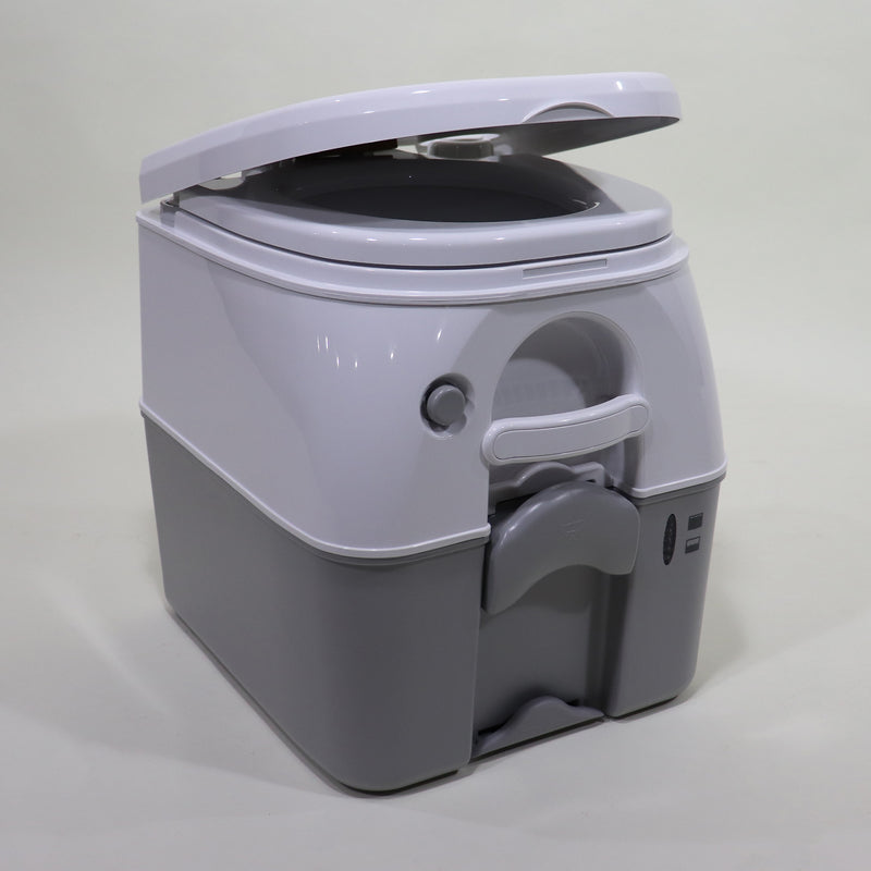A gray portable toilet, known as a Porta Potty, with its lid open, showcasing the interior and push-button flush mechanism.