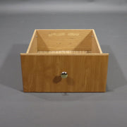 A beige wooden cabinet drawer with a metal handle.